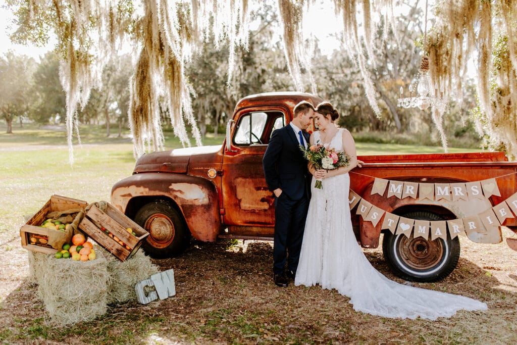 man and woman standing next to rustic truck on their wedding day